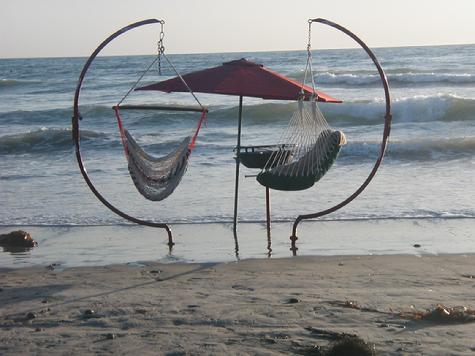 Two C-Frames with hanging Beach Swings, and a standing B-B-Q in the surf.